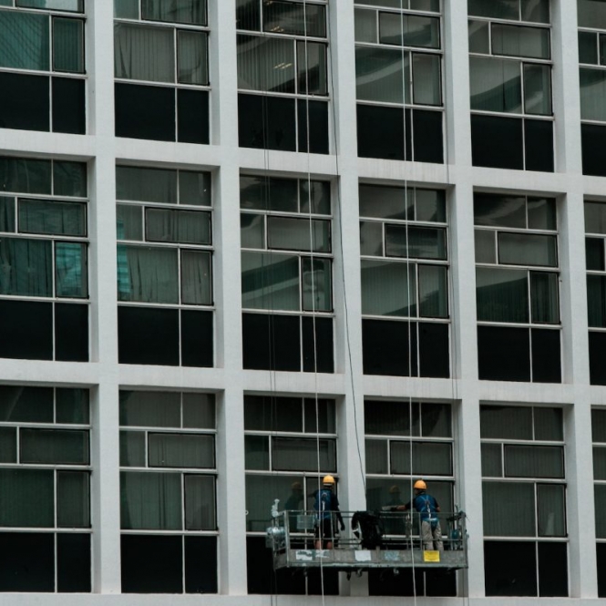a couple of men standing on a scaffold in front of a tall building
