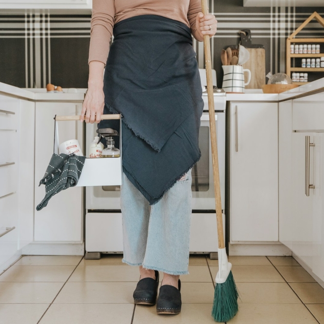a woman standing in a kitchen holding a broom
