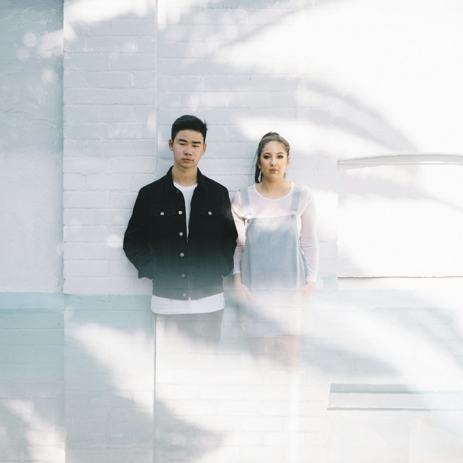 minimalist photography of man beside woman while leaning against wall