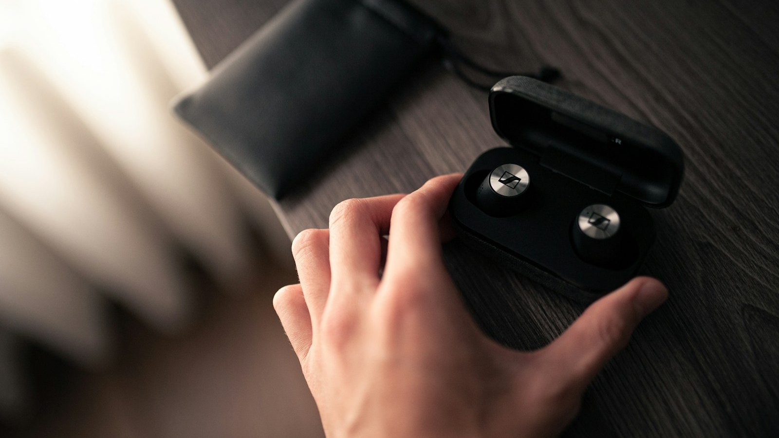 a person's hand holding a pair of black earbuds