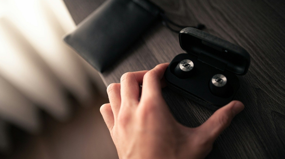 a person's hand holding a pair of black earbuds