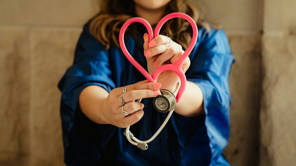 woman in scrubs holding heart shaped stethoscope