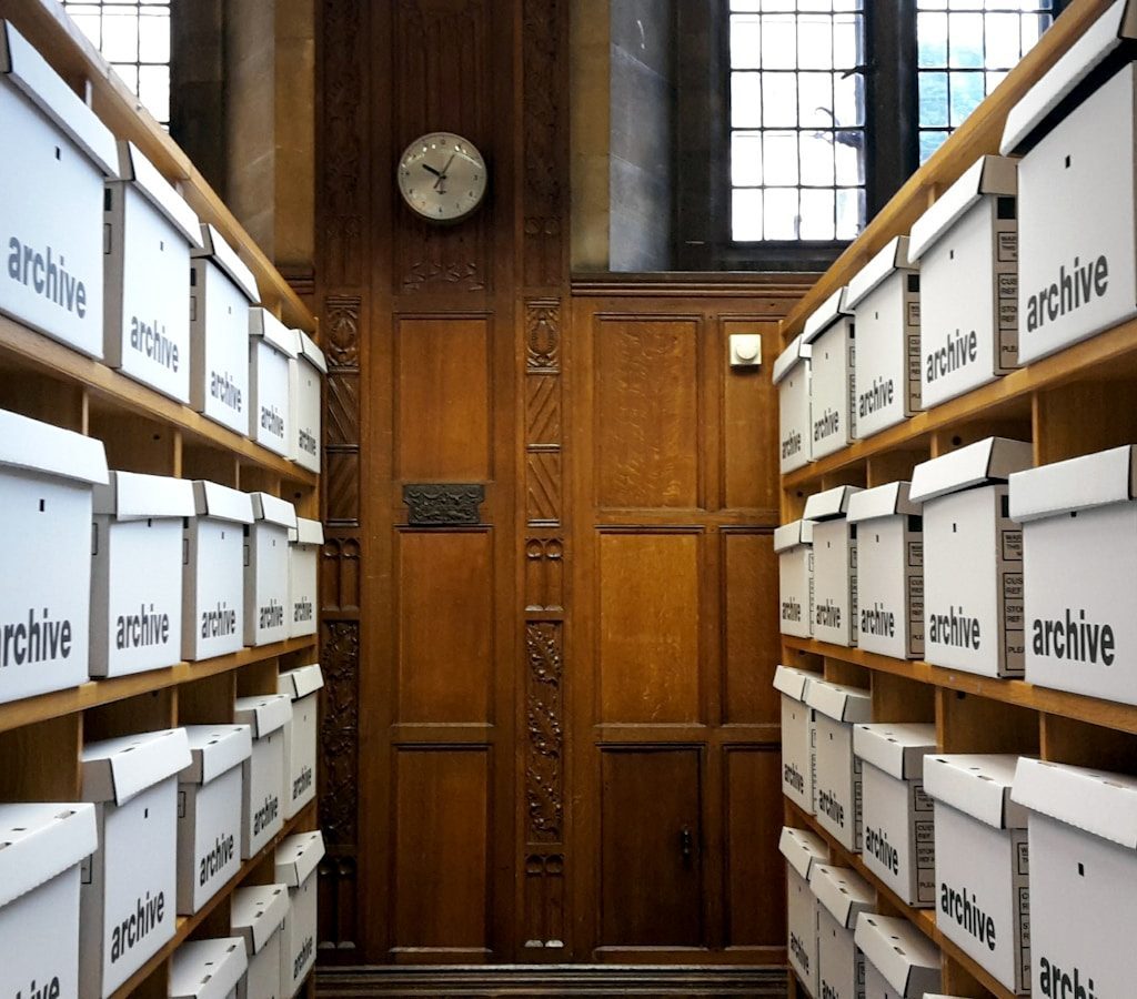 Rows of white archive boxes on wooden shelves
