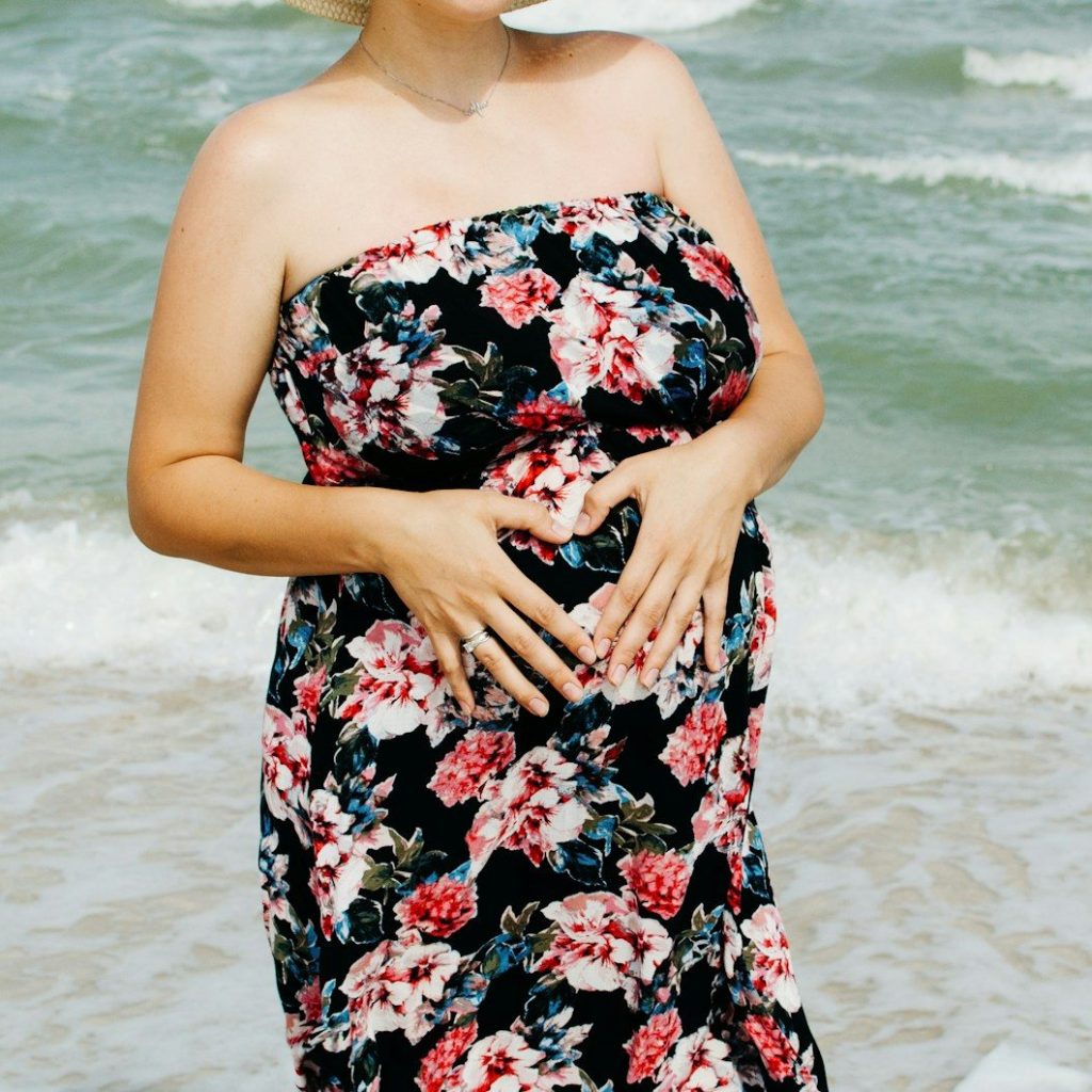 woman in black red and white floral tube dress standing on beach during daytime