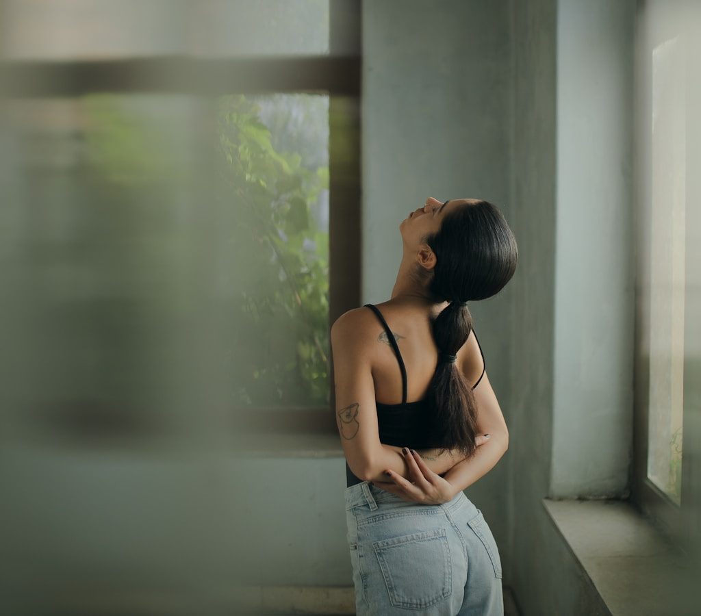 A woman leaning against a wall with her head in her hands