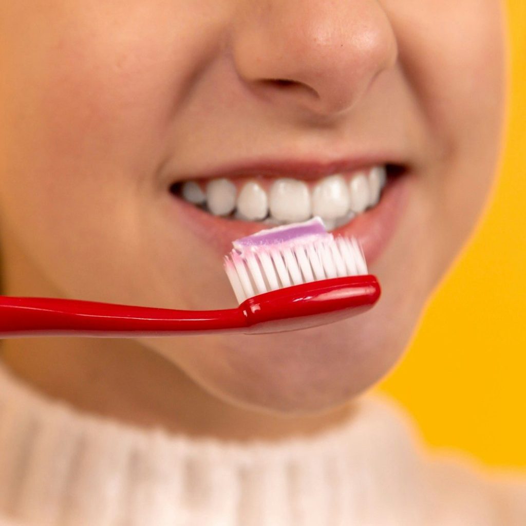 girl with red and white toothbrush in mouth