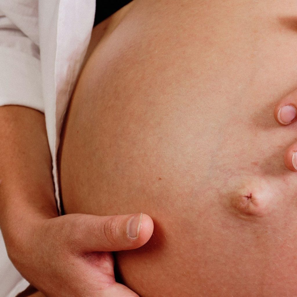 a close up of a person touching a pregnant belly